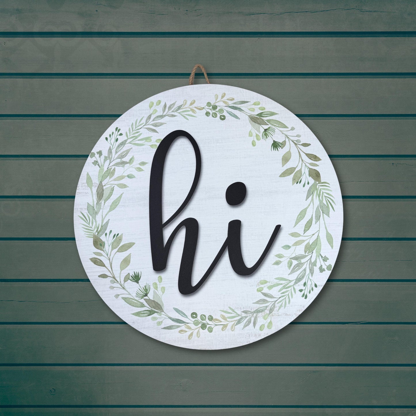 Round 'hi' door sign with black lettering and green botanical wreath on weathered teal wood background, farmhouse entryway decor