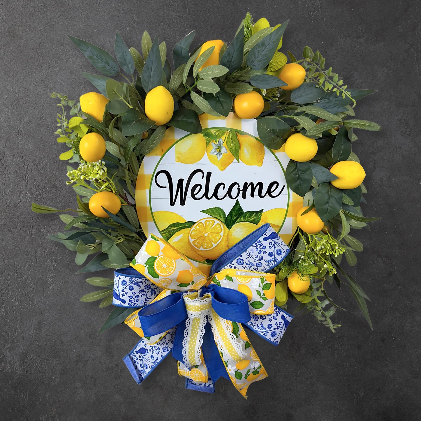 Handmade lemon welcome wreath with faux lemons, greenery, and layered blue and yellow bow, perfect for front door summer decor