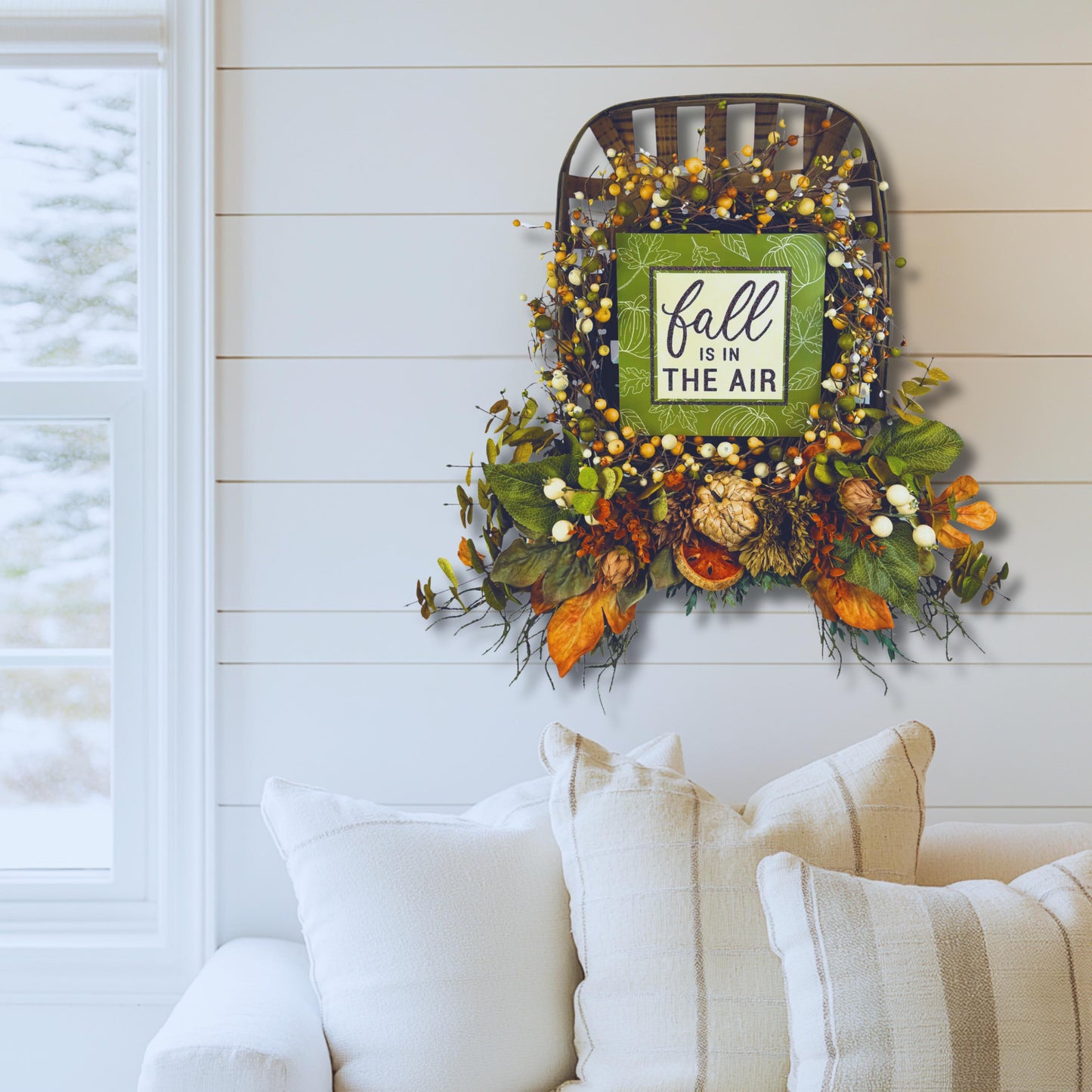 Indoor farmhouse fall wreath with tobacco basket hung above couch for cozy autumn décor