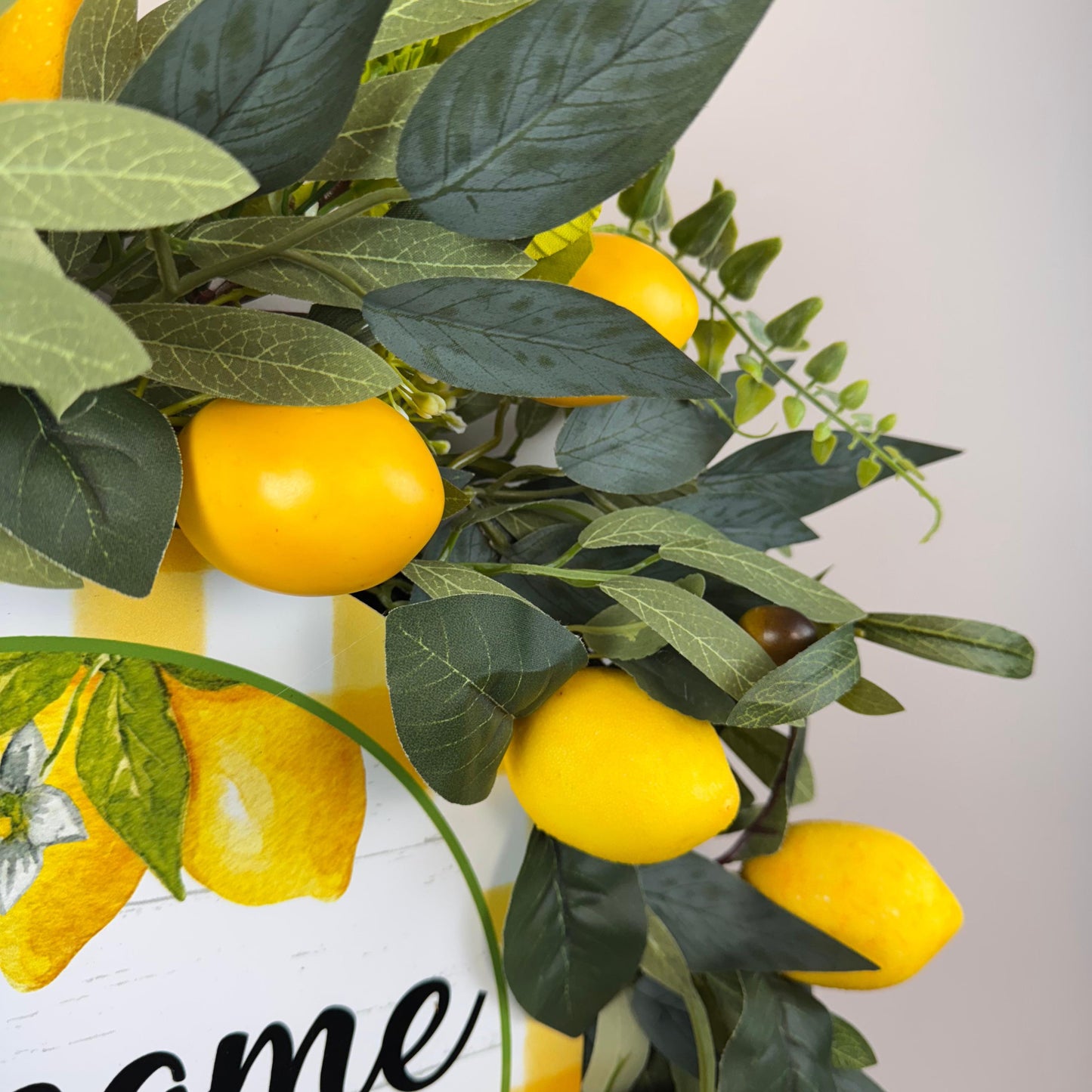 Zoomed-in photo of lifelike faux lemons and greenery on summer welcome wreath, great for citrus or farmhouse decor themes