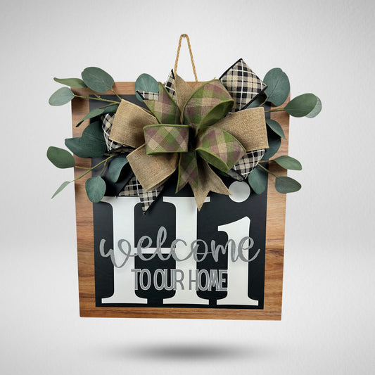 This handmade farmhouse welcome sign adds warmth to any home! Featuring a rustic wood finish, UV-printed text, and a plaid burlap bow, this 21" x 17.5" front door hanger is the perfect accent for porch decor, entryways, and housewarming gifts.