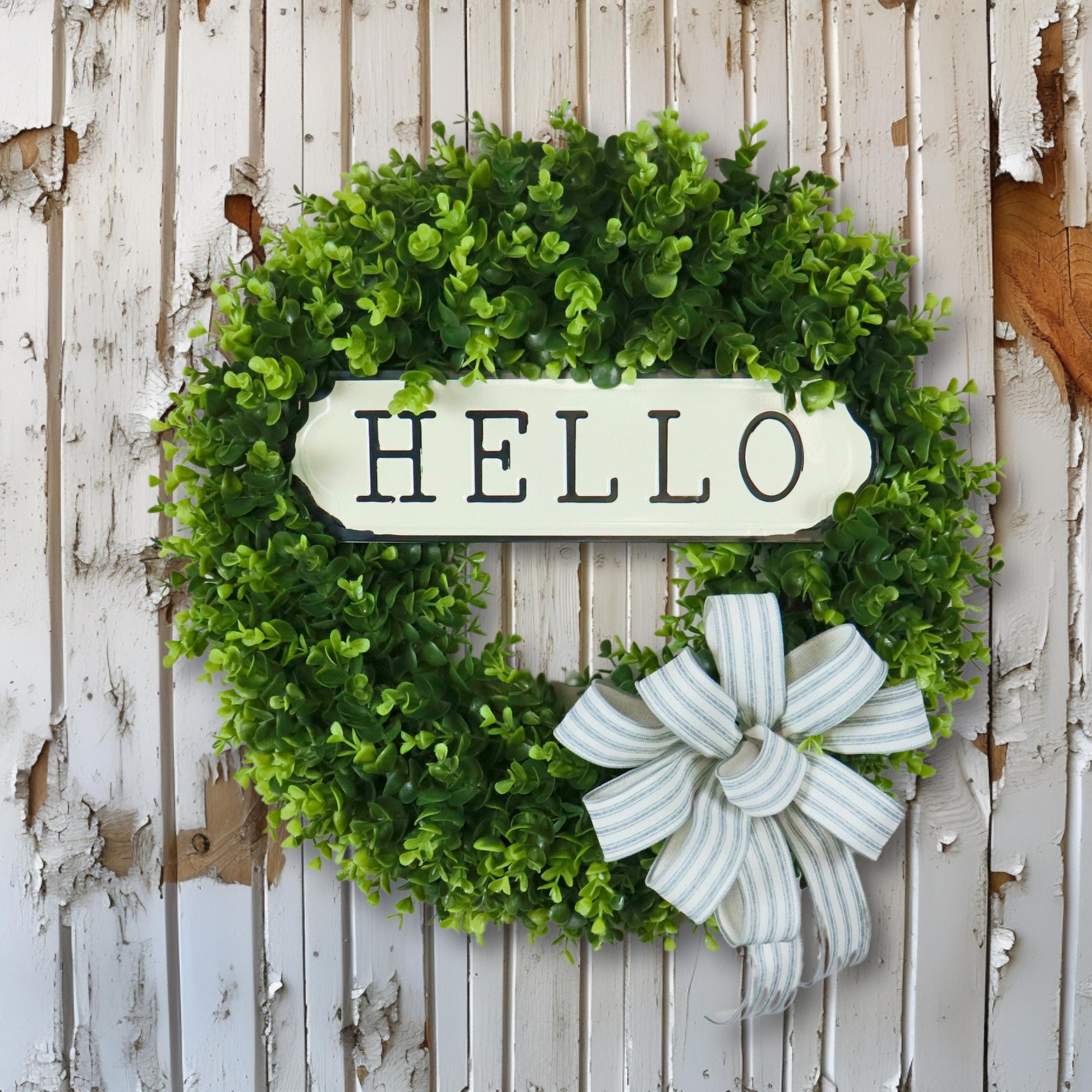 Farmhouse boxwood wreath with metal hello sign and striped bow, rustic front door decor, artificial greenery wreath for home entryway.