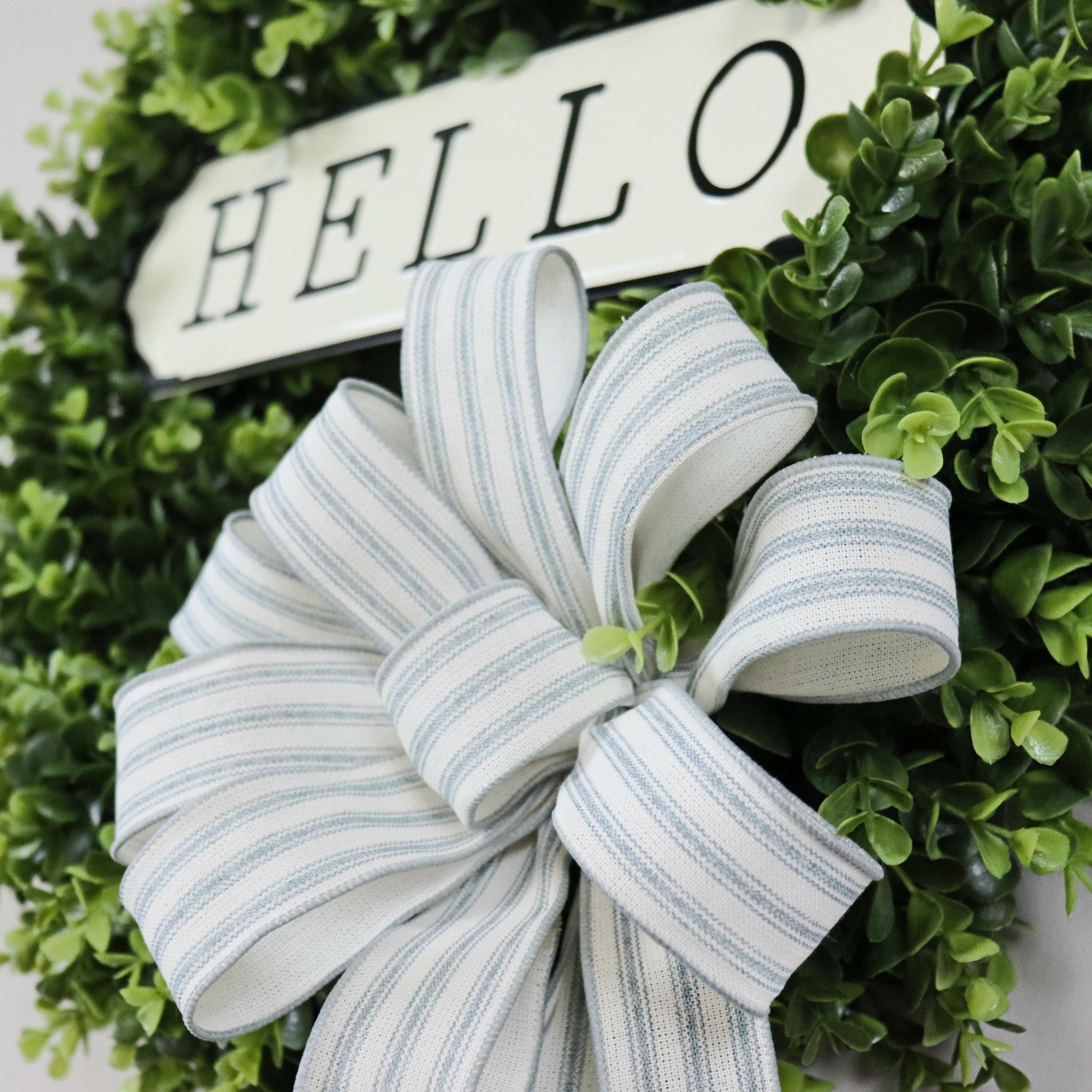 Hand-tied striped fabric bow on artificial boxwood wreath, neutral home decor, farmhouse front door wreath with elegant rustic details.