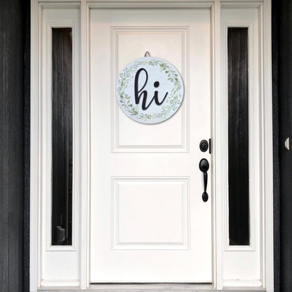 White door with black trim featuring round hi door sign with greenery wreath, modern farmhouse entryway decor for welcoming guests