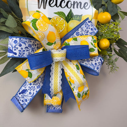 Detailed view of handcrafted bow with yellow lemon-print ribbon, blue floral accents, and lace trim on a summer door wreath