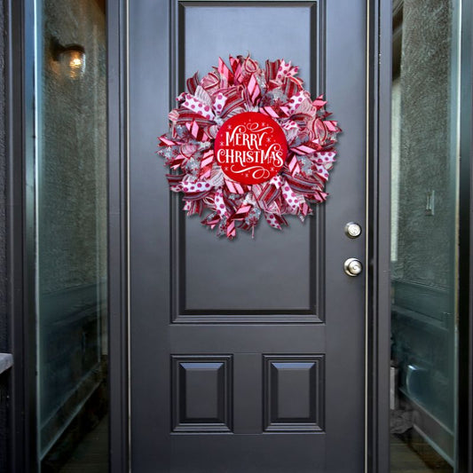 Red and white Christmas wreath with ribbon and a bold "Merry Christmas" sign, beautifully displayed on a front door for holiday celebrations.